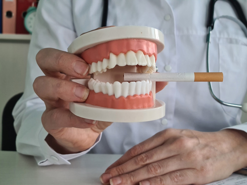 Dentist holding dentures with a cigarette in its teeth