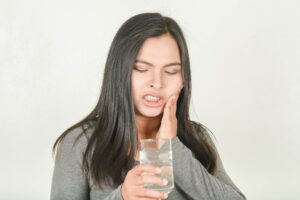 Woman experiencing tooth sensitivity after drinking cold water